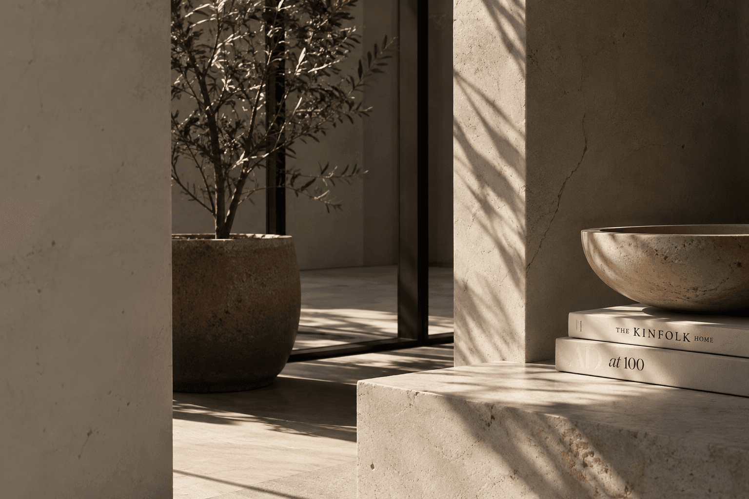 A stone basin, olive tree and stacked books in warm window light